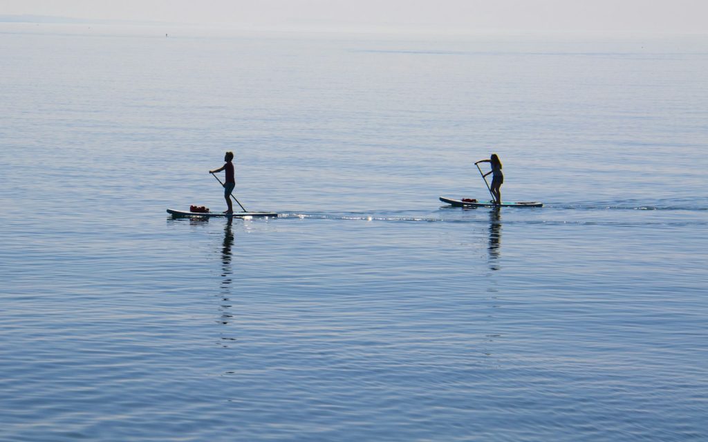 Deux personnes en stand up paddle sur un plan d'eau parfaitement calme